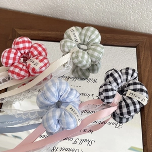 Detailed close-up of plaid flower scrunchies with long ribbons and delicate lace trim