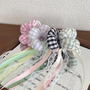 Detail of four plaid hair scrunchies with ribbons and lace on a mirror surface
