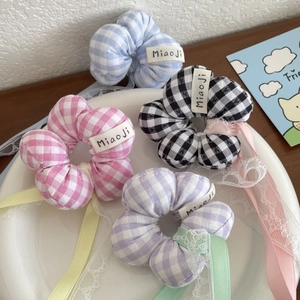 Set of four plaid floral hair scrunchies with ribbons and lace on a white ceramic plate