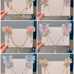 Détail de pinces à cheveux fleuries avec papillons et pompons pour tenues traditionnelles