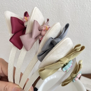 Dettaglio di cerchietti glitterati con fiocchi di seta e ciondoli unicorno in cinque colori