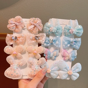 Detailed view of handmade pink and blue bow hair clips with embroidered floral patterns