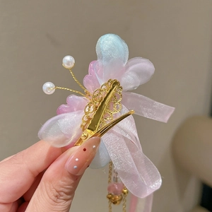 Détail de pince à cheveux papillon avec rubans roses et franges dorées élégantes
