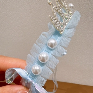 Detail of light blue lace princess headband featuring pearls and a rhinestone crown