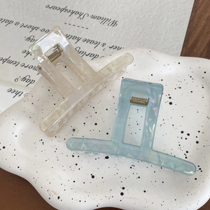 Macro view of geometric resin hair claws in cream and light blue with pearlescent finish