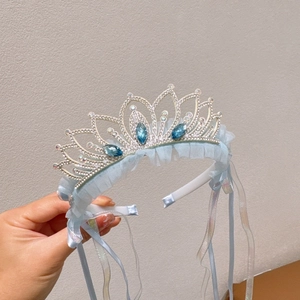 Detailed view of silver crown headband with blue rhinestones and light blue tulle ribbons