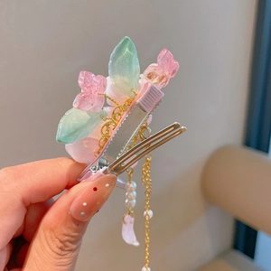 Détail de pince à cheveux fleur rose en résine avec pompons dorés et perles nacrées
