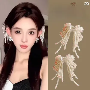 Detail of elegant pearl bow hair clip with tassels for side hair styling and fairy ear look