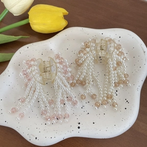 Elegant pearl tassel hair claws in pink and champagne colors on a ceramic tray