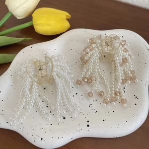 Detailed macro view of heart-shaped pearl fringe hair clips in white and champagne