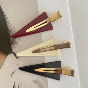 Close-up of three triangle acetate hair clips in burgundy cream and black colors