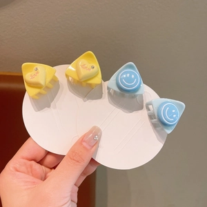 Close-up of mini resin hair claws with heart and smile designs in yellow and blue