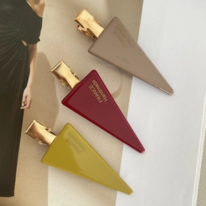 Detail view of acetate hair clips in burgundy, yellow, and khaki with gold metal clips
