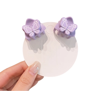 Pair of purple butterfly mini hair claw clips for girls on a white display card