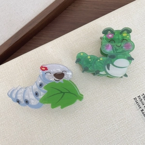 Detailweergave van schattige rups haarklemmen van acryl in groen en blauw met bloemen