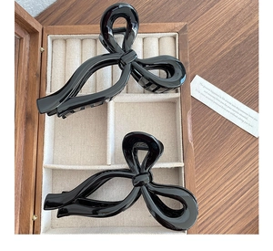 Détail de deux grandes pinces à cheveux à nœud noir sur un coffret à bijoux en bois