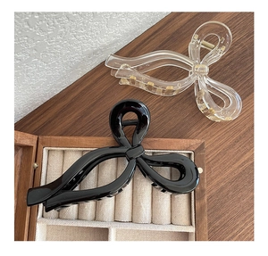 Détail de grandes pinces à cheveux de 13 cm avec nœud en noir poli et acrylique