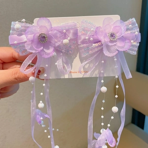 Detailed view of handmade purple flower hair clips with butterfly wings and pearl tassels