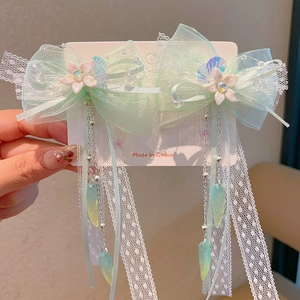 Detailed macro view of light green lace bow hair clips with flowers and long tassels