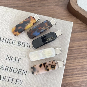 Flat lay of five French acetate hair clips in assorted marble and tortoise patterns