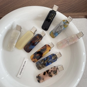 Detail view of acetate hair clips in eight assorted marbled and tortoiseshell patterns