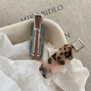 Detailed close-up of French acetate hair clips with gold lettering and marble texture