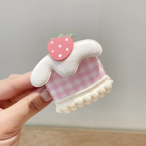 Dettaglio accessorio per capelli con fragola a quadretti rosa e morbida frangia pompon