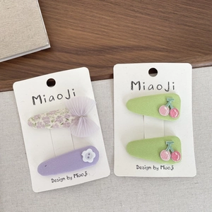 Détails de barrettes en tissu avec motifs floraux et broderies cerises sur carte