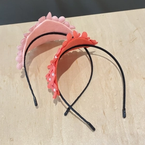 Detail view of pink felt flower headbands with elegant white pearl accents on wood