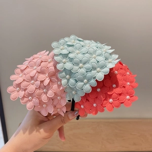 Close-up of floral headbands with 3D fabric flowers and pearls in pink, blue, and coral colors