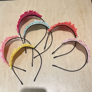 Detail of five colorful felt flower headbands for girls on a light wood background