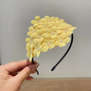 Detail of yellow fabric flowers with pearl centers on a non-slip hairband for girls