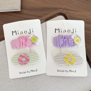 Détail de barrettes en tissu floral avec broderie donut et bordure en dentelle