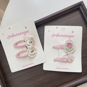 Detail der handgefertigten Stoffclips mit besticktem weißem Kaninchen und rosa Tulpe