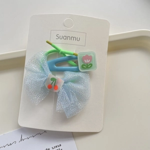 Close-up of blue mesh bow hair tie with cherry and tulip hair clip on a display card