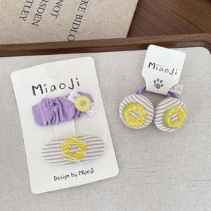 Vue détaillée du lot de barrettes à fleurs et chouchous avec décor de boutons jaunes