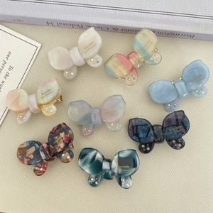 Detailed macro view of butterfly hair clips in eight pearlescent colors with rhinestone accents