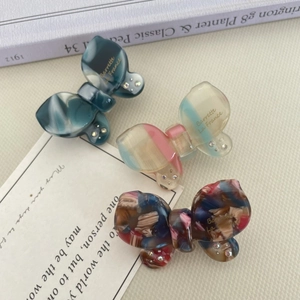 Detailed close-up of acetate butterfly hair clips with rhinestones and marble patterns