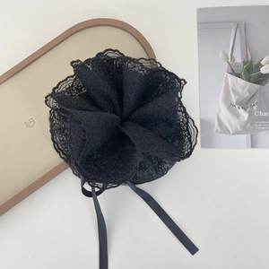 Detail of elegant black lace hair scrunchie with ribbons on a minimalist white backdrop
