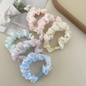 Set of 5 pastel satin scrunchies with colorful polka dots on a stylish background