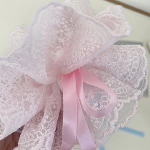 Macro shot of delicate pink lace fabric and silk ribbon detail on the floral hair tie
