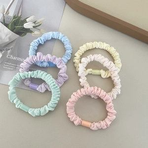Flat lay of macaron-colored pleated hair scrunchies with matching resin buckles