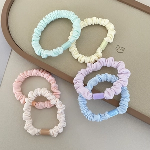 Detail of six colorful macaron fabric scrunchies with plastic decorative buckles