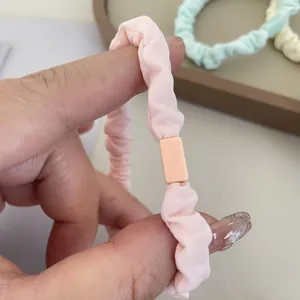 Detailed macro view of pink pleated knit scrunchie with plastic clasp in hand