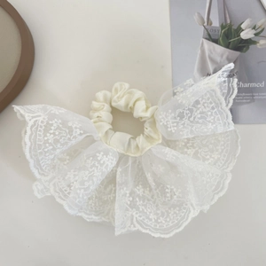 Detailed macro view of white lace scrunchie with floral embroidery and satin fabric