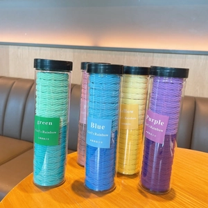 Macro detail of colorful wave pattern elastic hair ties in a clear cylindrical package