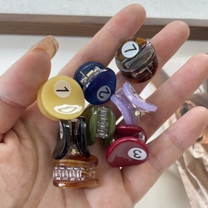 Mini billiard ball hair clips in various colors shown held in hand for size