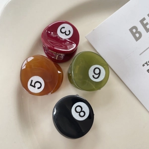 Close-up of four mini pool ball hair claws in red, amber, green and black colors