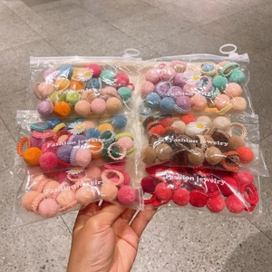 Set of 6 bags of colorful plush pom-pom hair ties and clips in clear zipper packaging