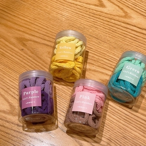 Lot d'élastiques à cheveux macaron en bocaux sur une surface en bois pour filles